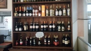 A wooden wine rack with multiple shelves holding various bottles of wine. - Matteo's Resort (Naivasha)