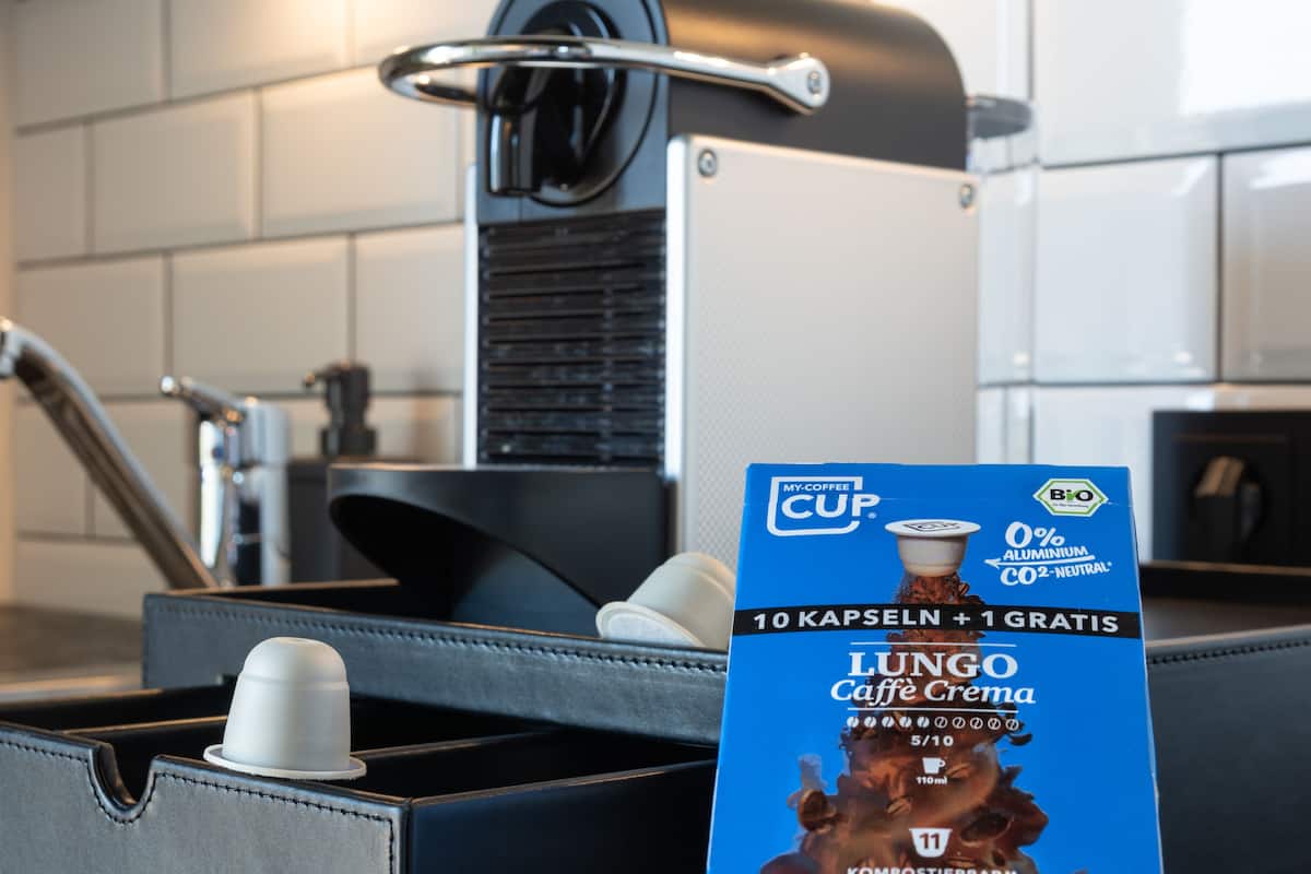 A kitchen with a coffee machine, a kettle, and a coffee pod holder.