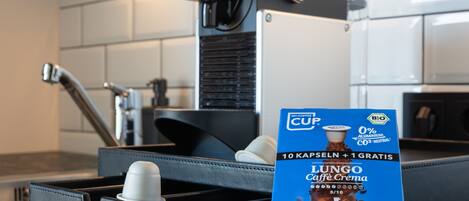 A kitchen with a coffee machine, a kettle, and a coffee pod holder.