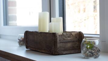 A rustic wooden block candle holder with three candles on a windowsill.
