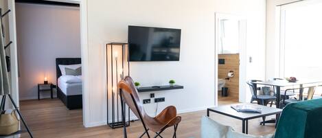 Una habitación de hotel moderna con cama, televisor, escritorio y zona de comedor.