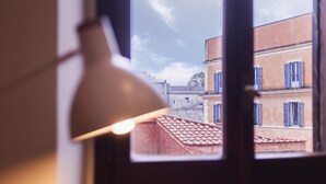Une fenêtre donnant sur des immeubles, avec une lampe placée au premier plan.