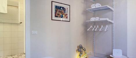 Habitación de hotel con cama, estante con toallas, un cuadro enmarco y una lámpara decorativa.