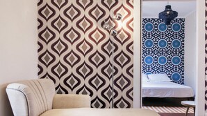 Une chambre moderne avec un papier peint à motifs, un canapé, un lit et un luminaire suspendu.
