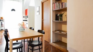 A dining area with a wooden table and black chairs, a bookshelf with books and a vase, and a door leading to another room. - Garibaldi RTH (Rome)
