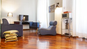 A modern living room with a flat-screen TV, a sofa, a chair, and a coffee table. - Garibaldi RTH (Rome)