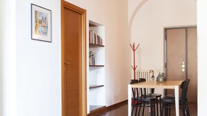 A spacious room with a wooden floor, a dining table with chairs, a bookshelf, and a door. - Garibaldi RTH (Rome)