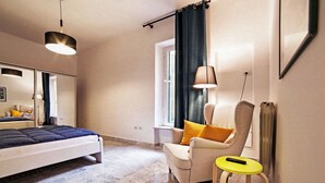 Un dormitorio moderno con una cama, una silla, una mesita y una ventana con cortinas.