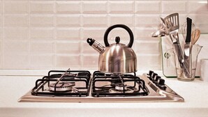 Una cocina con estufa a gas de acero inoxidable, un hervidor y un cajón debajo.