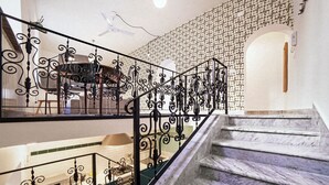 Una escalera con barandillas de metal negro ornamentado y escalones de mármol.