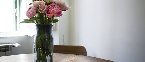 Un jarrón con flores sobre una mesa de madera junto a una ventana.