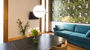 Un comedor con una mesa de madera oscura, un jarrón de flores blancas y un sofá azul.
