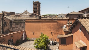A courtyard with terracotta-tiled roofs, a bell tower, and a small tree. - Genovesi RTH (Rome)