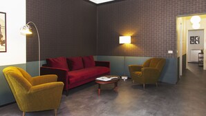 A room with a red sofa, yellow armchair, and a small round table. - Genovesi RTH (Rome)