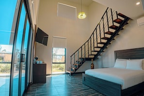 A modern bedroom with a large bed, a wooden staircase, and a glass door leading to an outdoor area. - Quinta Nicolás Valle de Guadalupe (Valle de Guadalupe)