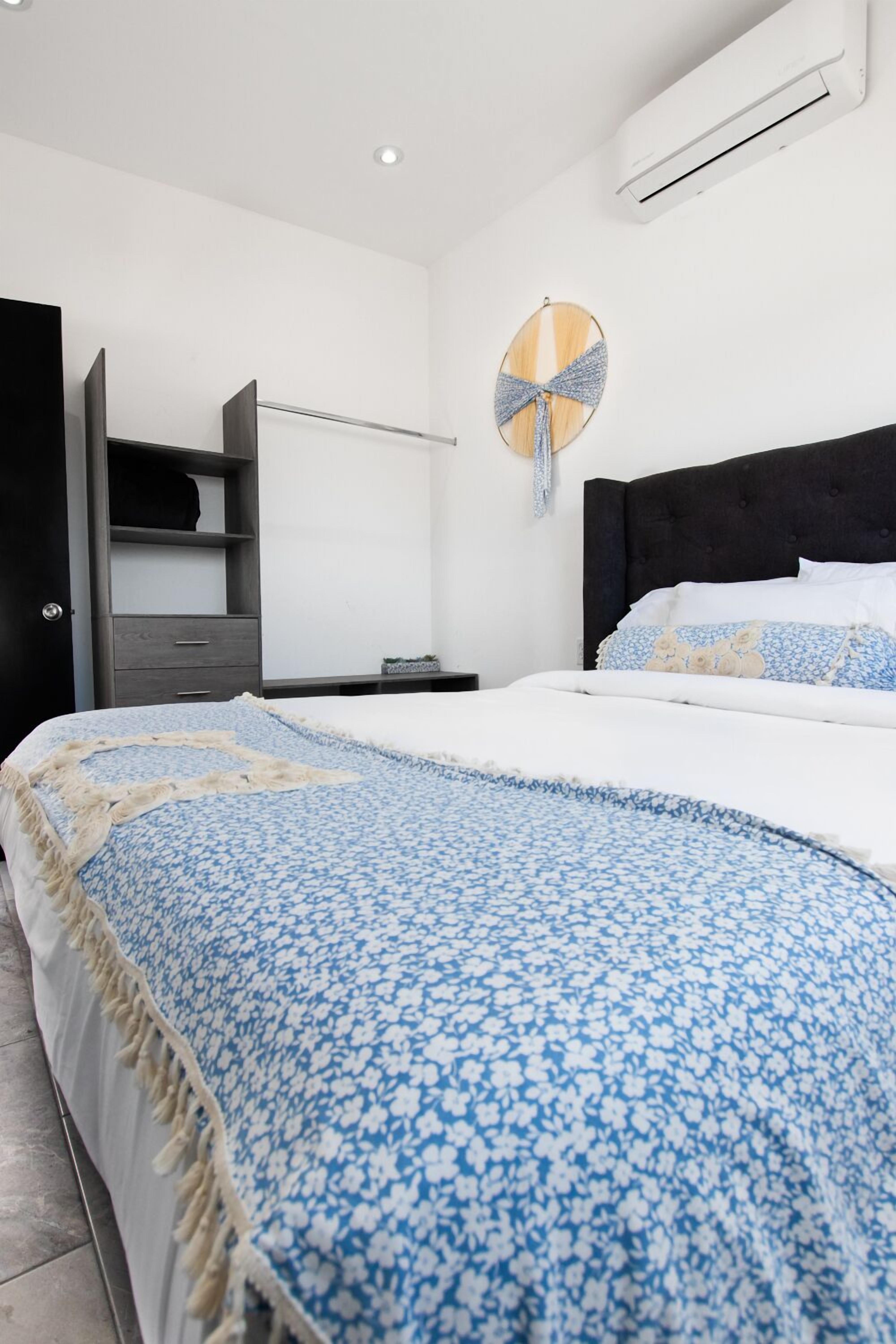 Un dormitorio moderno con cama, armario, espejo redondo y unidad de aire acondicionado.