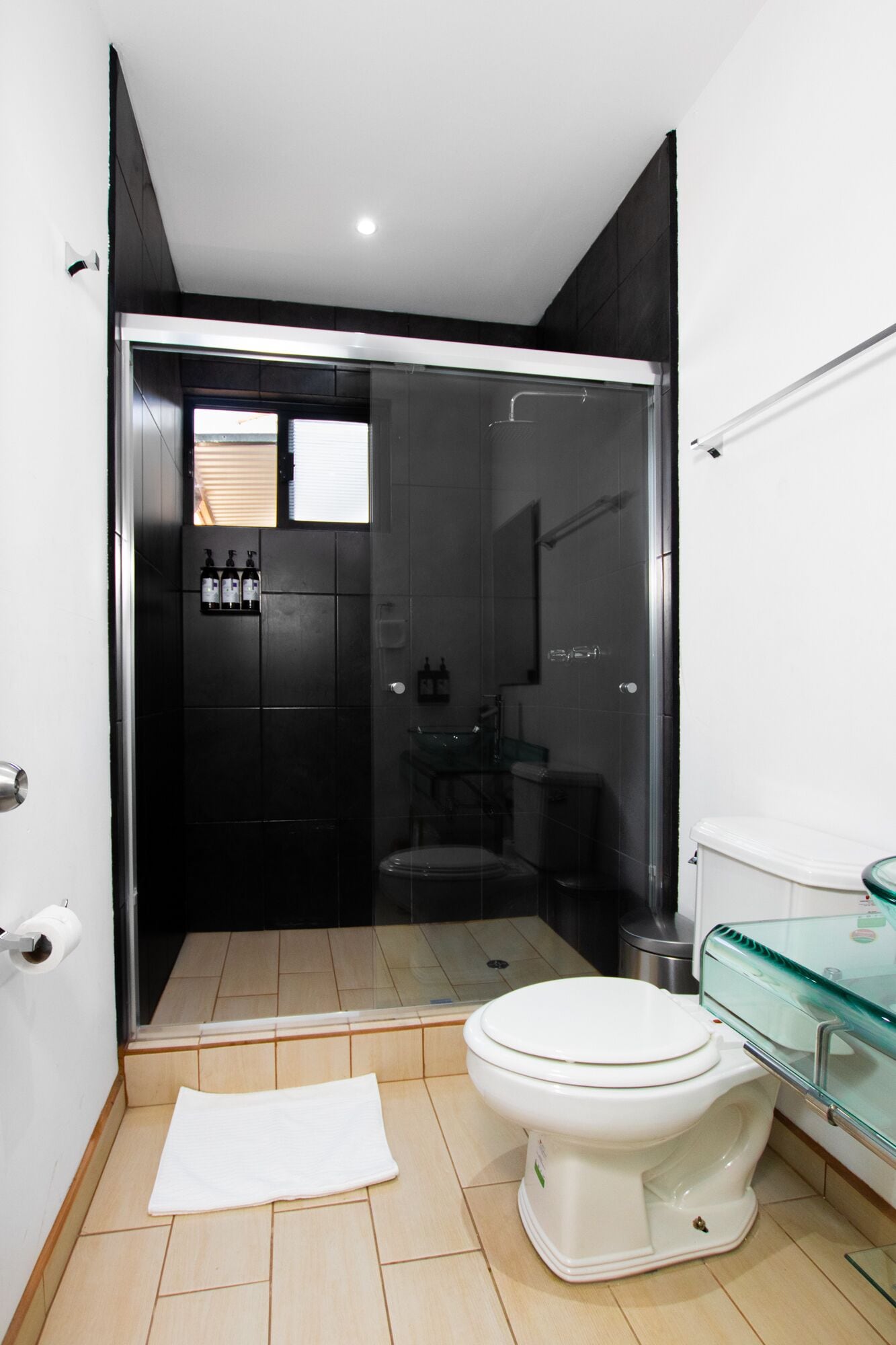 Un bagno moderno con cabina doccia in vetro, un water bianco e un lavandino in vetro.