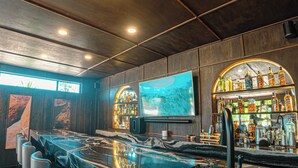 A bar area with a marble countertop, bar stools, a television, and shelves of liquor bottles. - Quinta Nicolás Valle de Guadalupe (Valle de Guadalupe)
