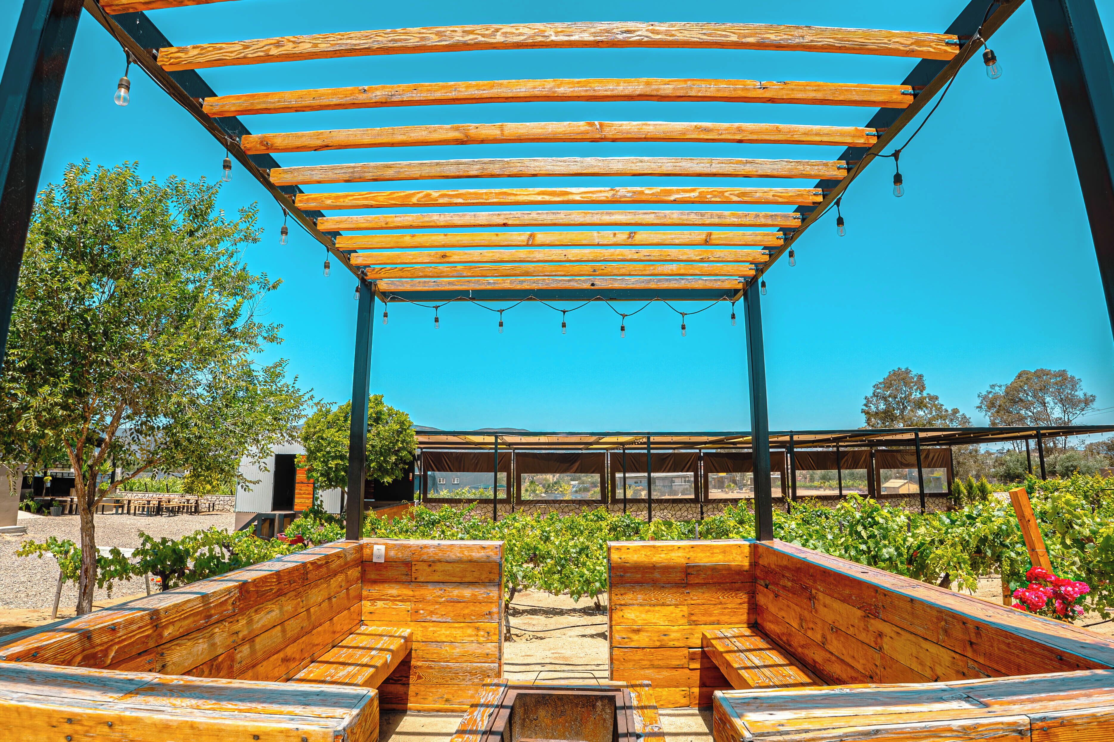 Een overdekt terras met houten banken en een pergola.