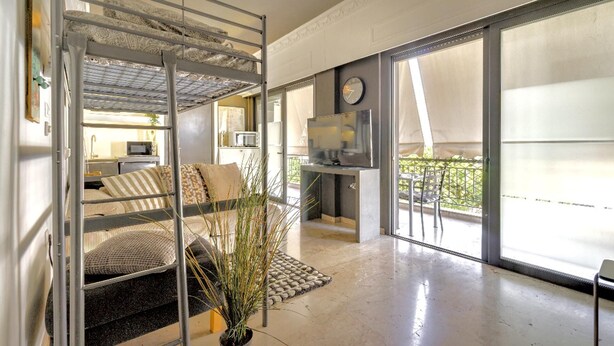 A modern interior with a bunk bed, a kitchen area, and large windows. - Impeccable 3-bed Apartment in Athens (Nea Ionia)