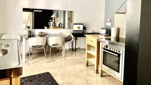 A modern kitchen with a Bosch oven, a dining area with white chairs, and a large mirror reflecting the room. - Impeccable 3-bed Apartment in Athens (Nea Ionia)