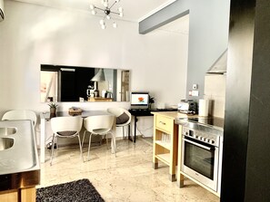 A modern kitchen with a Bosch oven, a dining area with white chairs, and a large mirror reflecting the room.