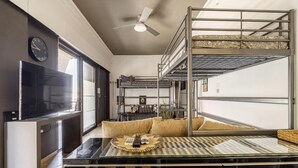 A compact room with a bunk bed, a flat-screen TV, a small table with a woven tray, and a window with a view. - Impeccable 3-bed Apartment in Athens (Nea Ionia)