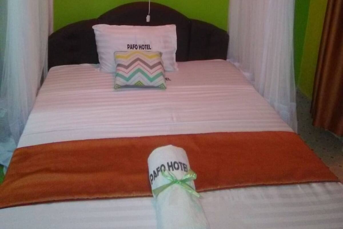 A bed with a green headboard, white curtains, and a pillow with a zigzag pattern.