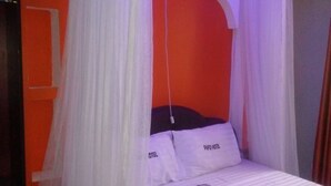 A bed with a canopy, white bedding, and pillows labeled "PAFO HOTEL". - Pafo Hotel (Kisumu)