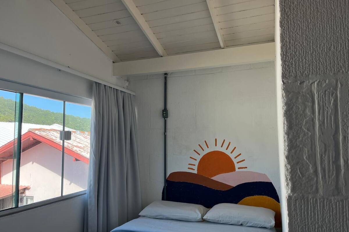 Un dormitorio con una cama, una ventana con cortinas y una pared con un diseño de sol.