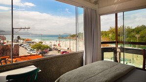 Un balcón con vista a la playa, una cama y una mesa con sillas.