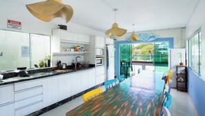 Una cocina moderna con armarios blancos, una mesa de comedor de madera y lámparas colgantes.