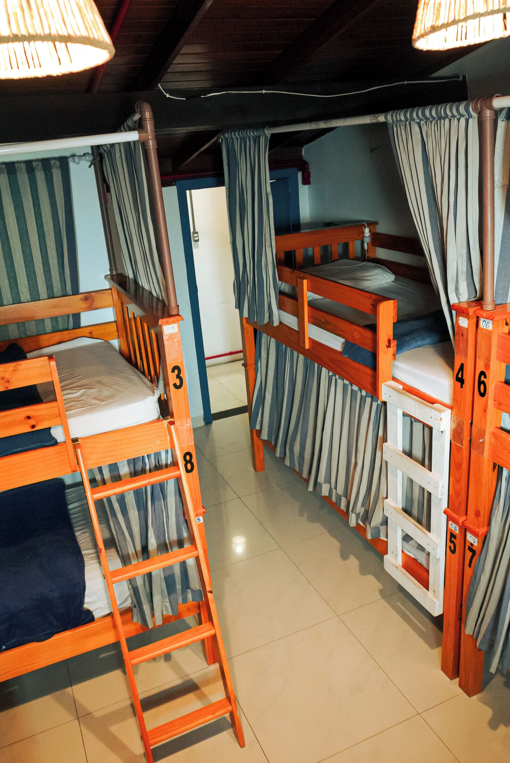 A dormitory room with bunk beds, a ladder, and curtains.