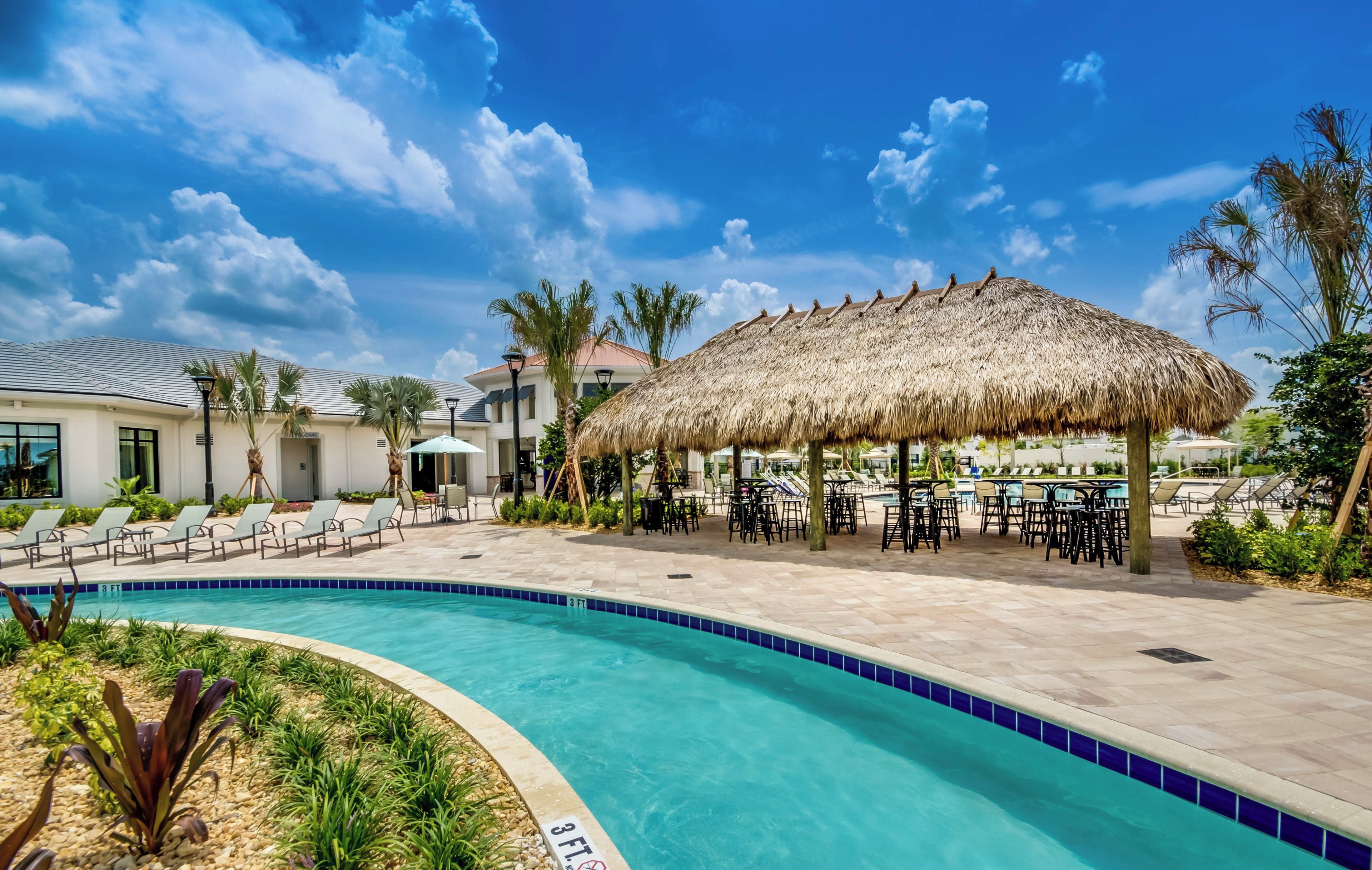 A resort pool area with a thatched umbrella, lounge chairs, and a clear blue pool.