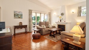 Ein Wohnzimmer mit einer Couch, einem Couchtisch, einem Kamin und einem Fernseher.