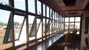 A long bar area with high windows and a view of the outside. - The Baron Hotel (Thika)