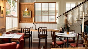 Un restaurant avec des boiseries, une grande fenêtre et un escalier.
