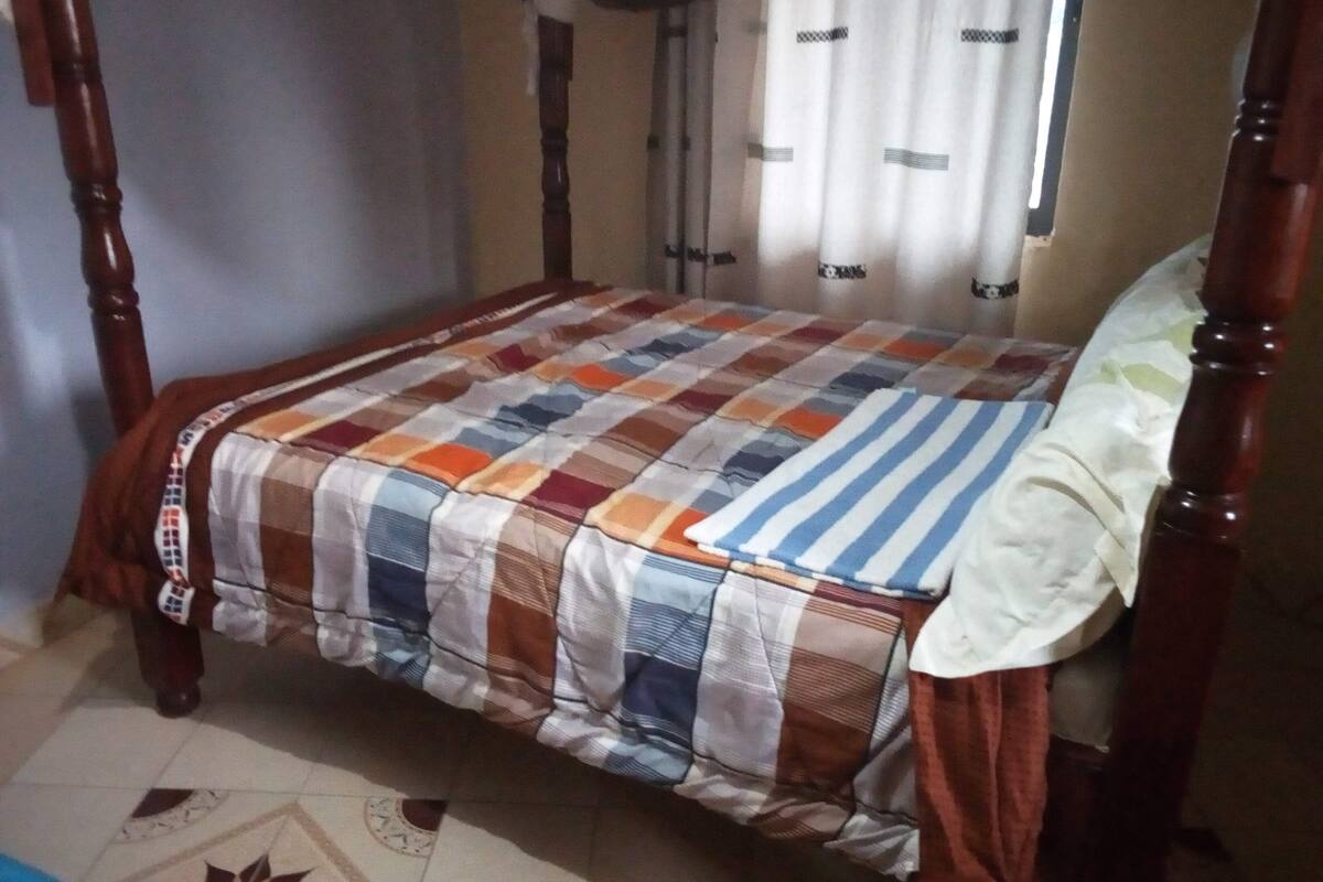 A four-poster bed with a checkered bedspread and a striped pillow.