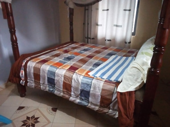Ein Himmelbett mit kariertem Bettbezug und einem gestreiften Kopfkissen.