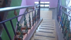 Un escalier avec des rampes en métal et un mur violet en haut.