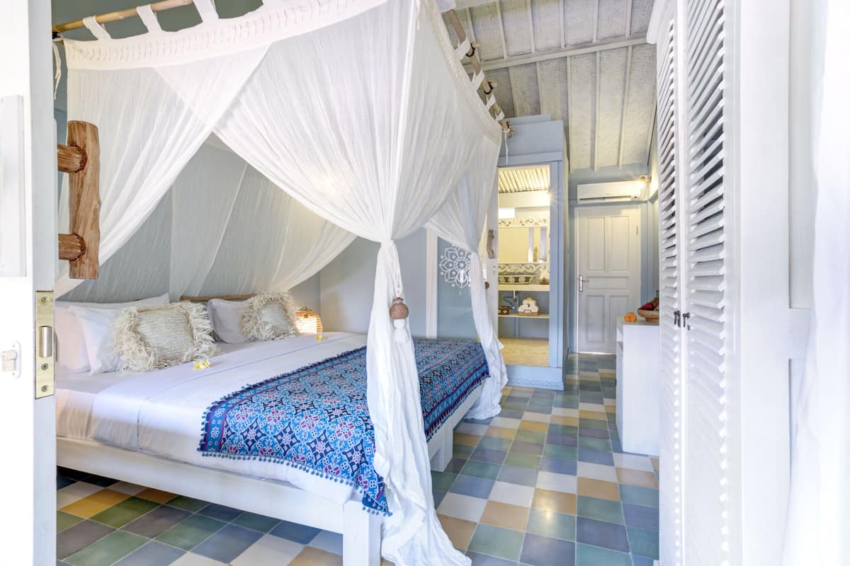 A four-poster canopy bed with a patterned bedspread, a small bedside table, and a nightstand.