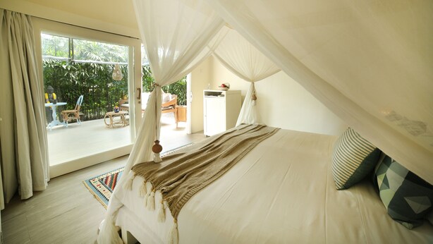 A bedroom with a canopy bed, a view of the outdoor area, and a small table with chairs. - The Chillhouse Canggu (Canggu)