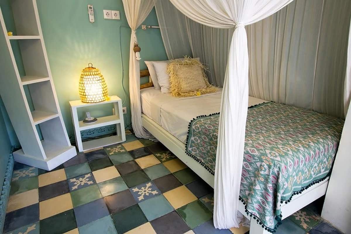 A bedroom with a bed, a nightstand, a lamp, and a checkered floor.