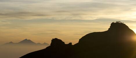 A mountain silhouette with a group of people at the peak.