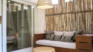 A cozy corner with a cushioned bench, a wicker stool, and a bamboo wall. - The Chillhouse Canggu (Canggu)