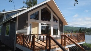 Une cabane moderne dotée d’une grande terrasse et offrant une vue sur le lac.