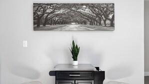 Eine moderne Küche mit schwarzer Arbeitsplatte, zwei weißen Barhocker und einem Blumentopf.