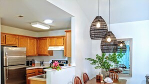 A modern kitchen with wooden cabinets, a stainless steel refrigerator, and a dining area with a wooden table and chairs. - RARE⭐️DownTown Matthews ❤️Walk to Shops Restaurants Hiking❤️20 min to Charlotte (Matthews)