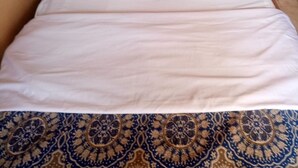A bed with a headboard, white bedding, and a patterned rug. - Witas Lodge (Nakuru)