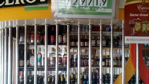 A liquor store with a variety of alcohol bottles on shelves behind metal bars. - Witas Lodge (Nakuru)